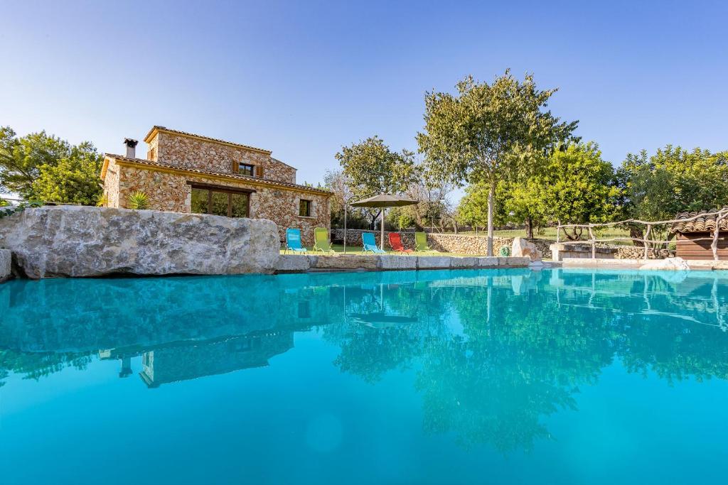 uma piscina de água azul com uma casa ao fundo em Villa Coric em Inca