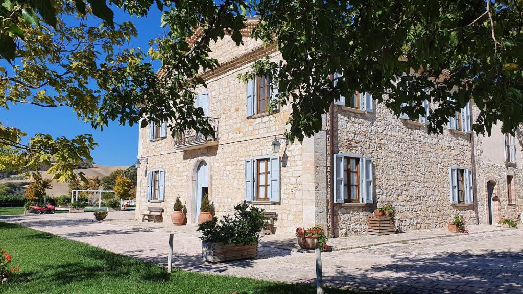 un gran edificio de piedra con plantas delante de él en I Casali di Colle Monte, en San Giuliano di Puglia