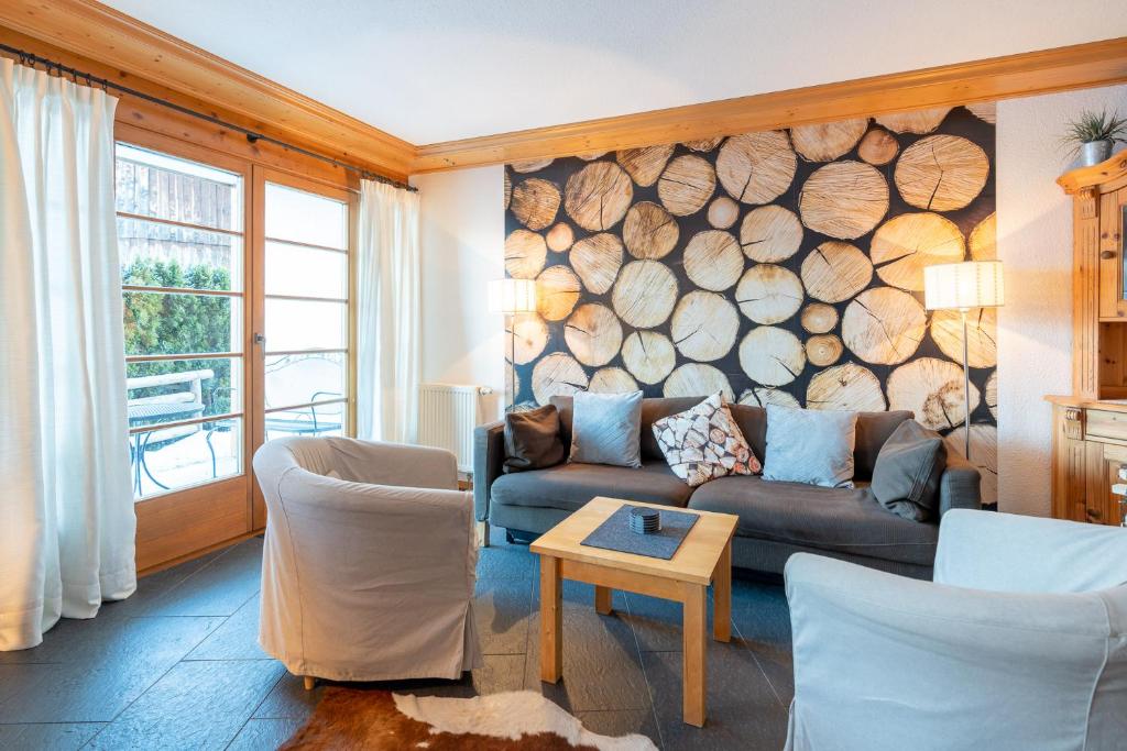 un soggiorno con divano e un muro di tronchi di Alpendomizil 3 a Bolsterlang
