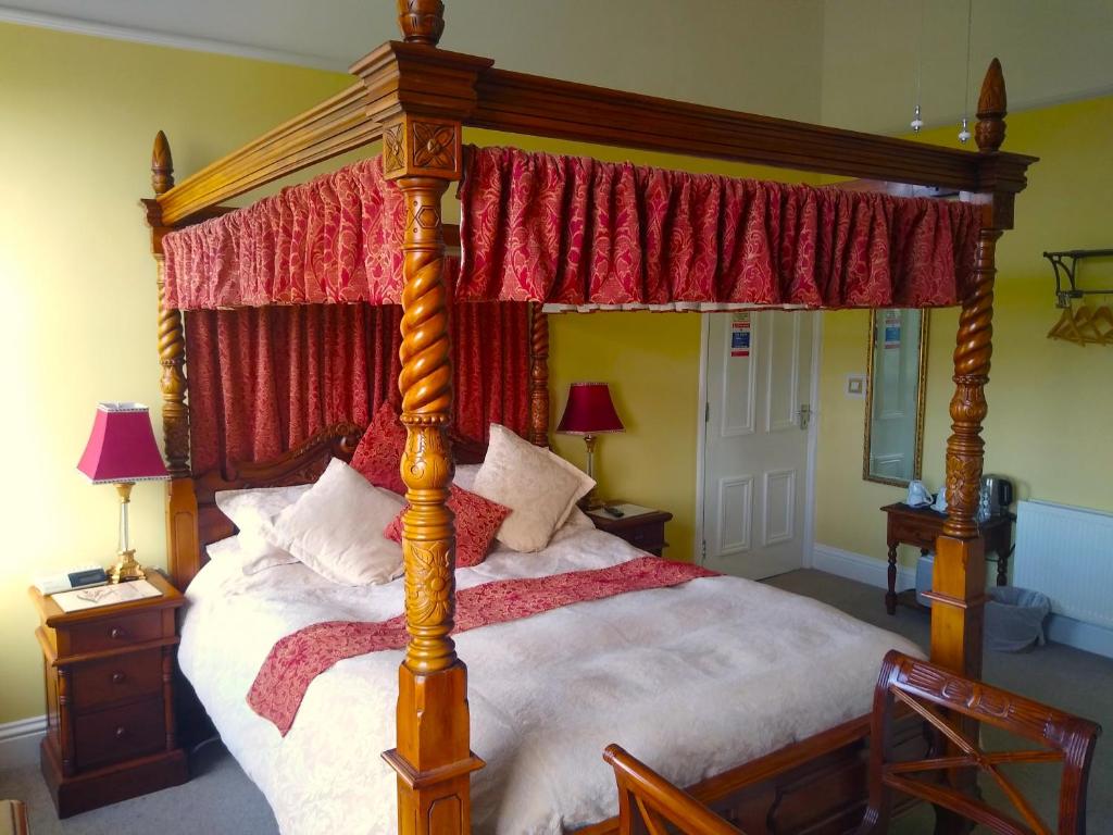 een slaapkamer met een hemelbed en rode gordijnen bij Green View Guest House in Silloth