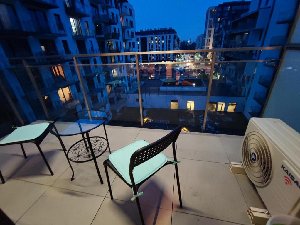 a balcony with two chairs and a table with a view of a city at Apartamenty Wola in Warsaw