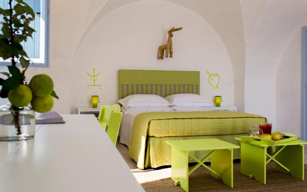 a bedroom with a bed with green furniture and tables at Masseria Corte degli Asini in Montalbano