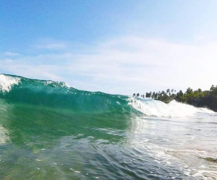 a large wave in the ocean on a beach at Goyambokka Guesthouse in Tangalle