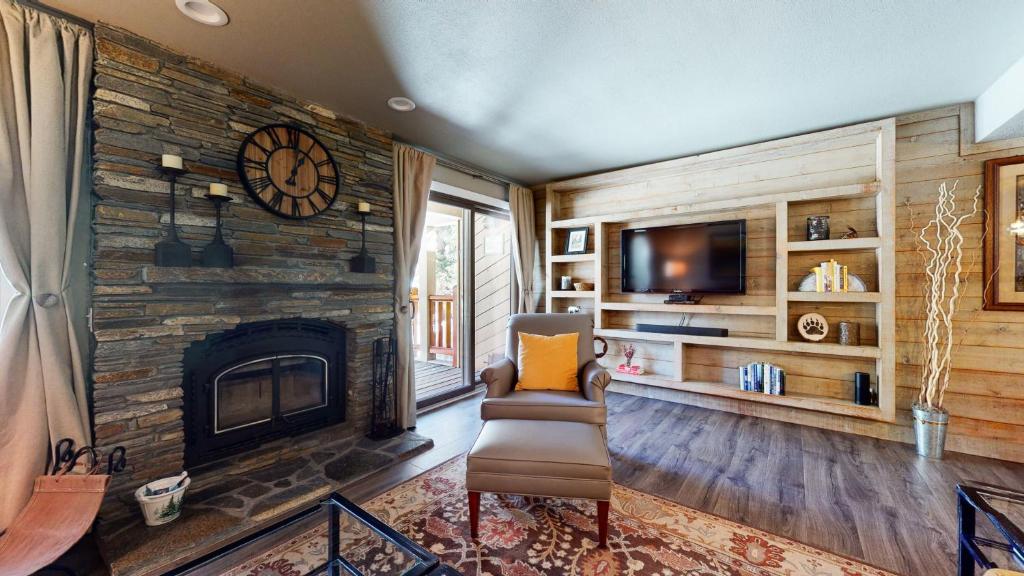 a living room with a stone fireplace and a television at Mammoth Creek #9 condo in Mammoth Lakes
