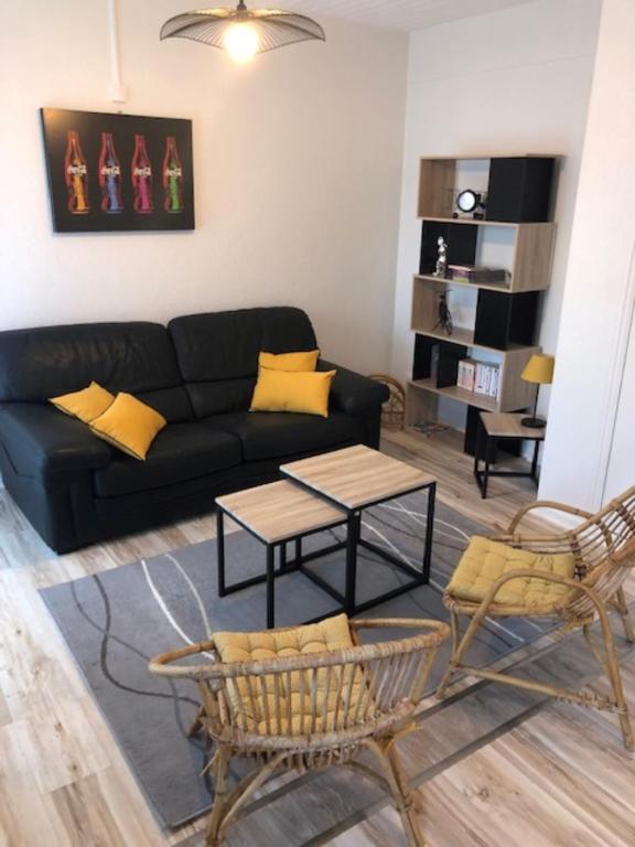 a living room with a black couch and a table at Hôtel Beau Rivage in Royan