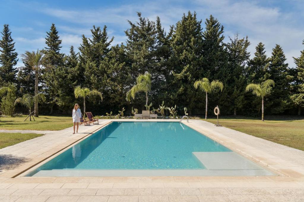 uma mulher está ao lado de uma piscina em Masseria Casina Baronale em Serrano