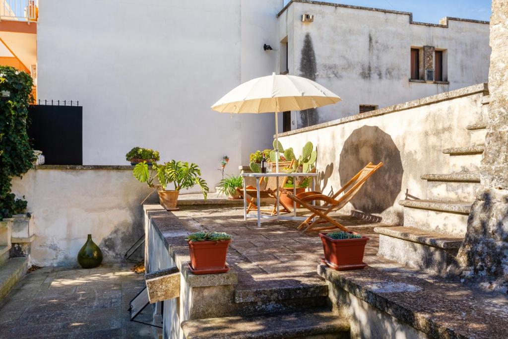 um pátio com uma mesa e um guarda-chuva em Domus Perrone Garden White em Squinzano