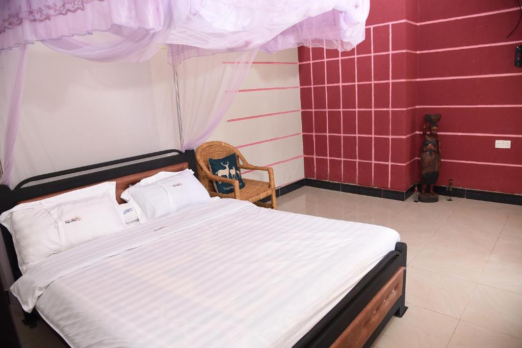 a bedroom with a bed and a chair at Trinity Resort Hotel & Spa in Kampala