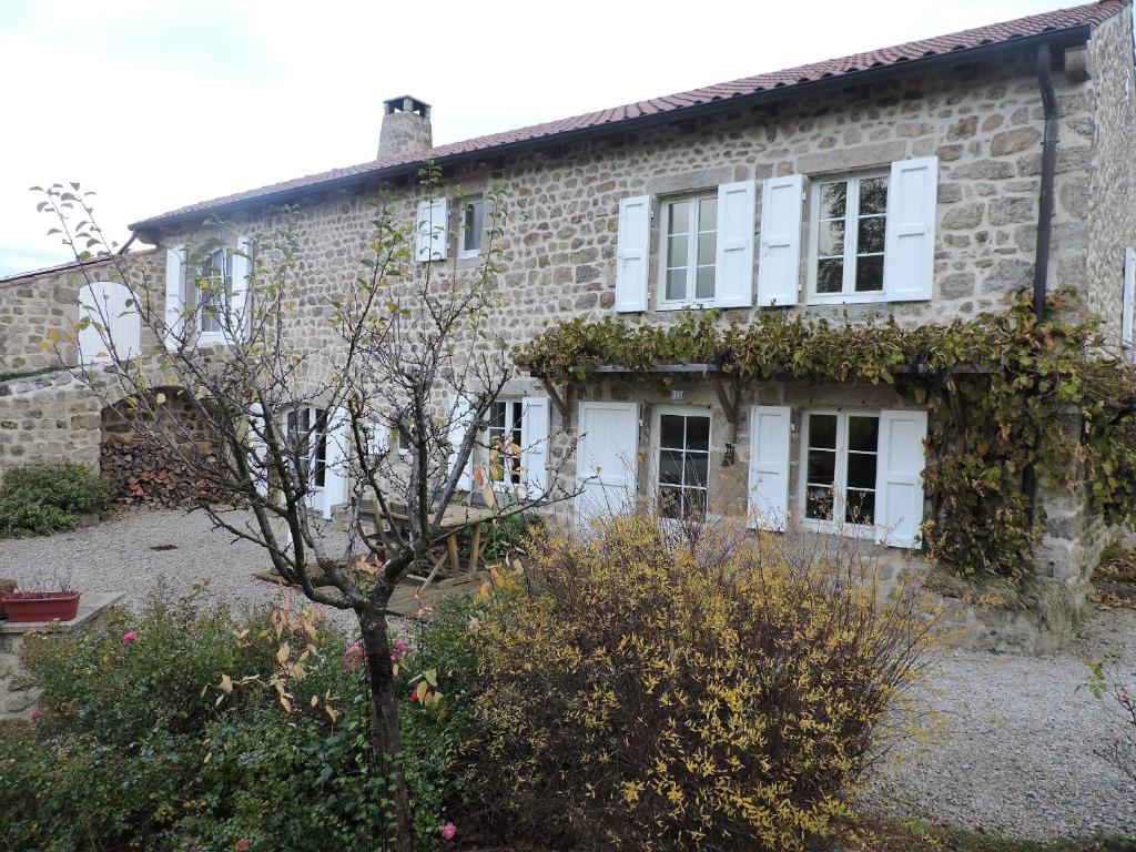 una vieja casa de ladrillo con un árbol delante en La sérénité en Grazac