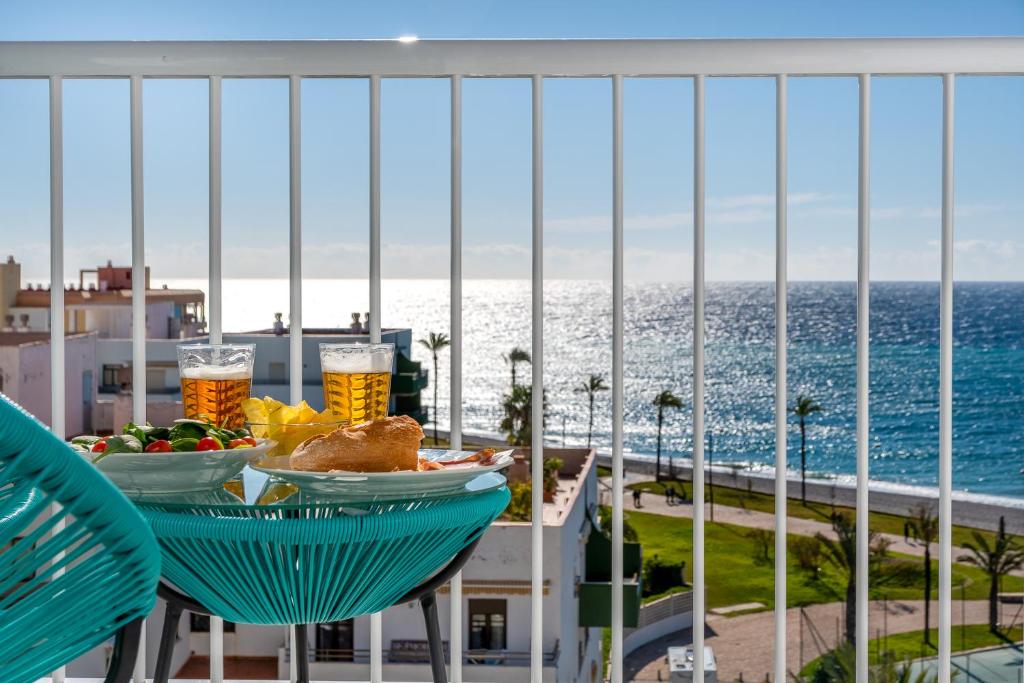 a table with food and drinks on a balcony with the ocean at Estudio 7 in Salobreña