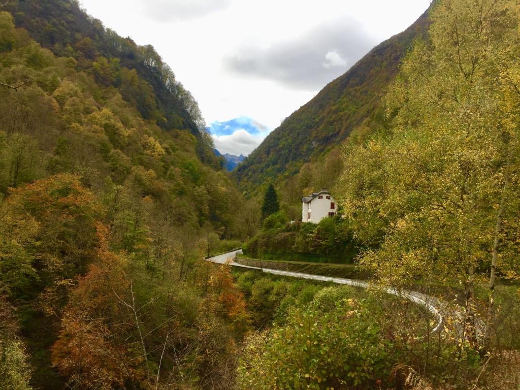 une route sinueuse dans une vallée de montagne avec une maison blanche dans l'établissement Les Ruisseaux, à Cauterets