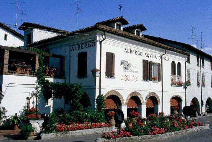 un edificio azul y blanco con flores delante en Hotel Arnaldo Aquila D’oro, en Rubiera