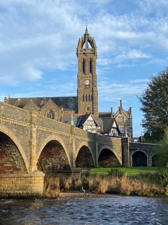 um edifício com uma torre de relógio e uma ponte em Tweed Green Holiday let em Peebles