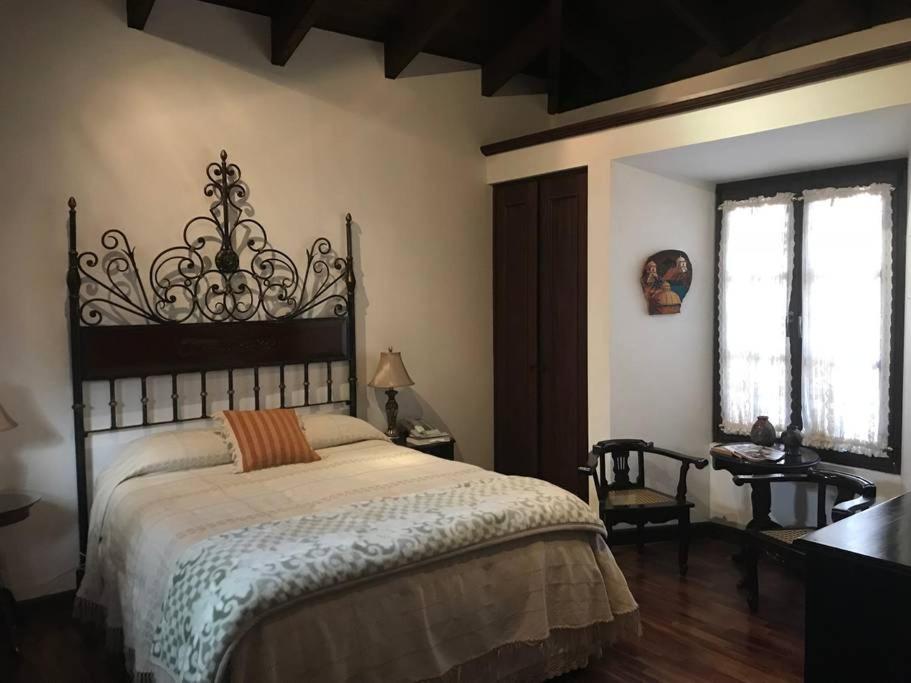 um quarto com uma cama, uma secretária e 2 janelas em Casa de Antaño em San Cristóbal El Bajo