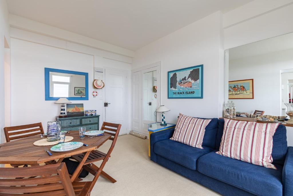 a living room with a blue couch and a table at Le Celtic in Saint-Cast-le-Guildo