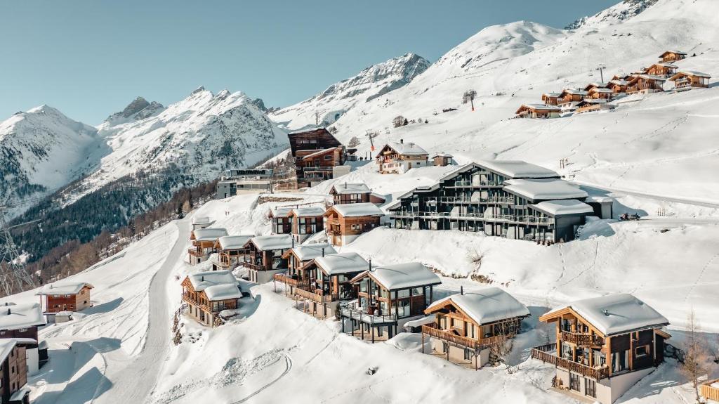 Lauchernalp Resort Residences في Wiler: قرية جبلية مغطاة بالثلج مع المباني