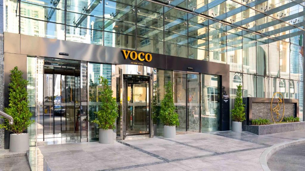 voco - Bonnington Dubai, an IHG Hotel في دبي: مبنى voxo مع نباتات الفخار أمامه