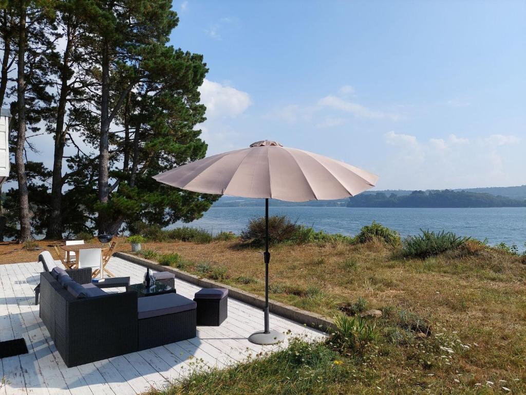 a white umbrella and a couch and a chair at Holiday home in a secluded location surrounded by the sea, Hanvec in Hanvec