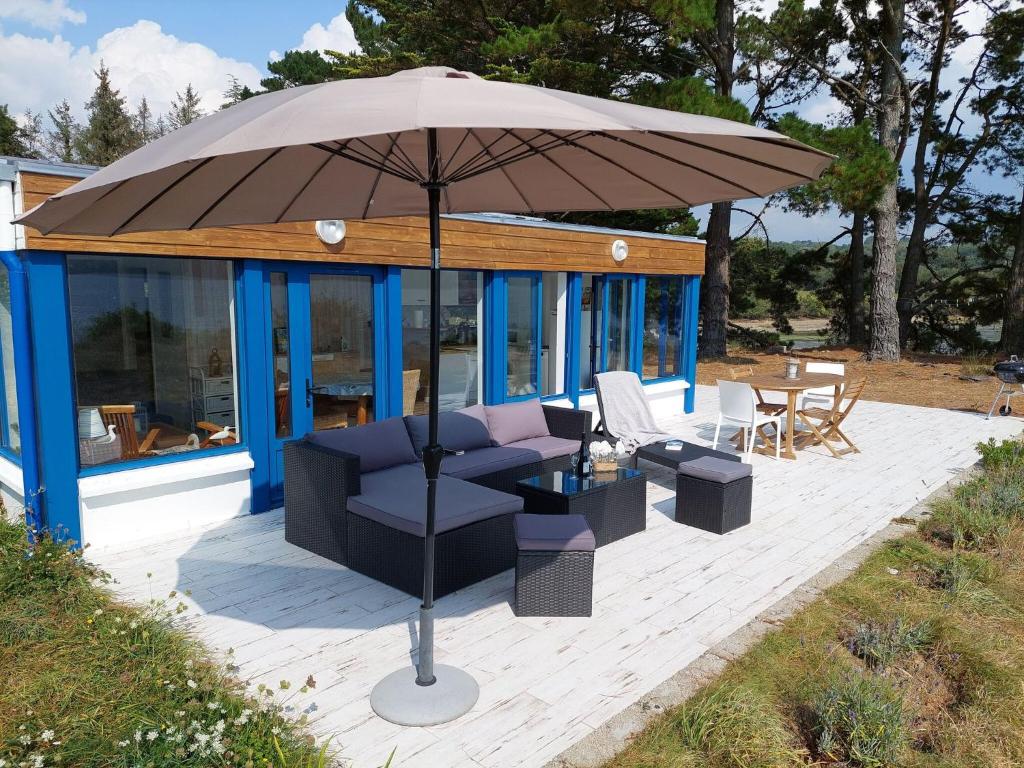 a patio with a couch and an umbrella at Holiday home in a secluded location surrounded by the sea, Hanvec in Hanvec