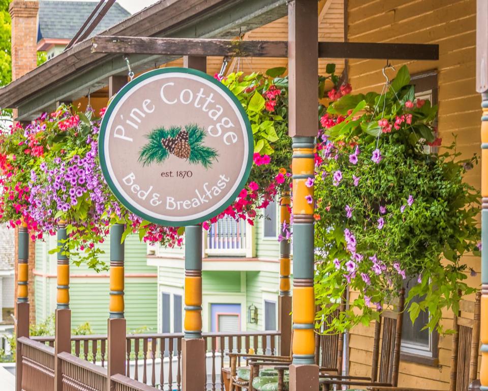 um sinal em frente a um edifício com flores em Pine Cottage Bed & Breakfast em Mackinac Island