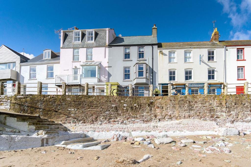 a large house on the beach next to a stone wall at Fred's Place - Kingsand in Kingsand
