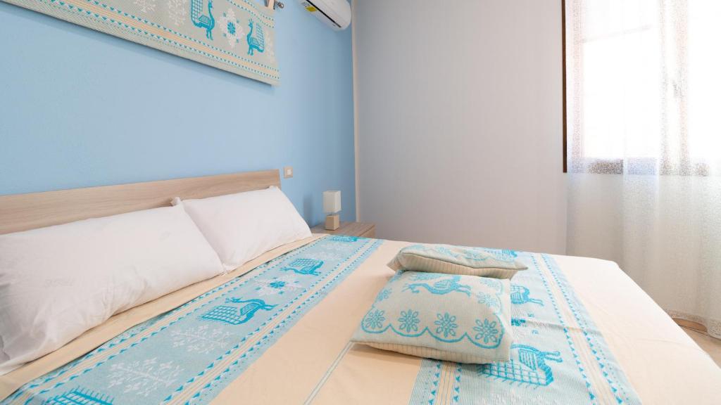 1 dormitorio azul con 1 cama con 2 almohadas en Welcomely - Il Lentischio en Càbras