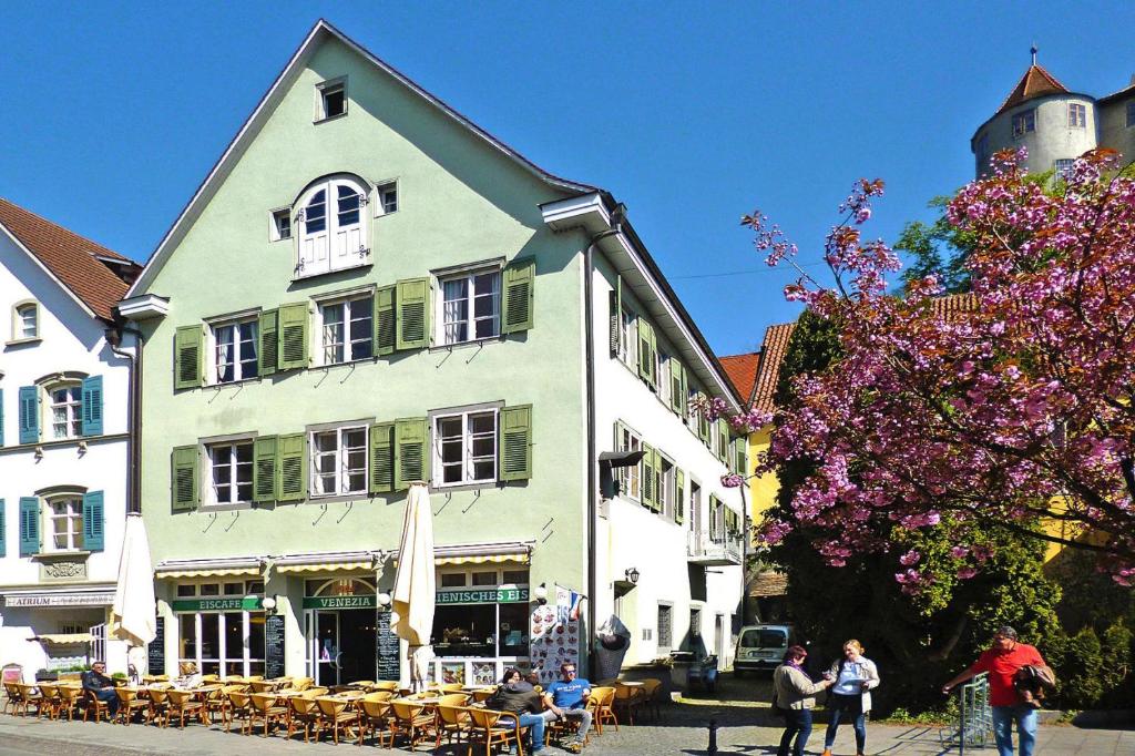 Un grand bâtiment blanc avec des personnes assises à l'extérieur dans l'établissement Apartment in Meersburg right on the water, à Meersburg