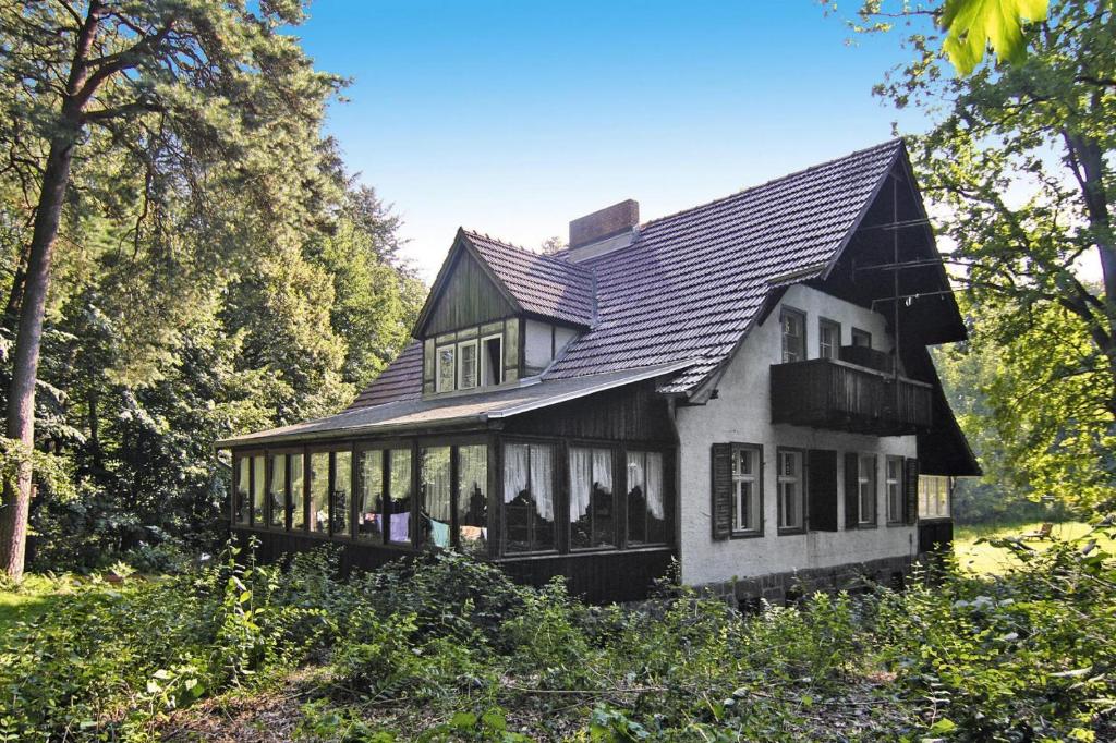 una casa en blanco y negro en medio de árboles en Cottage, Schorfheide, en Schorfheide