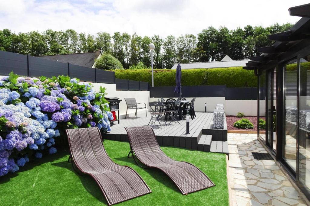 un patio con sillas y un jardín con flores púrpuras. en Cottage, Perros Guirec en Saint-Quay-Perros