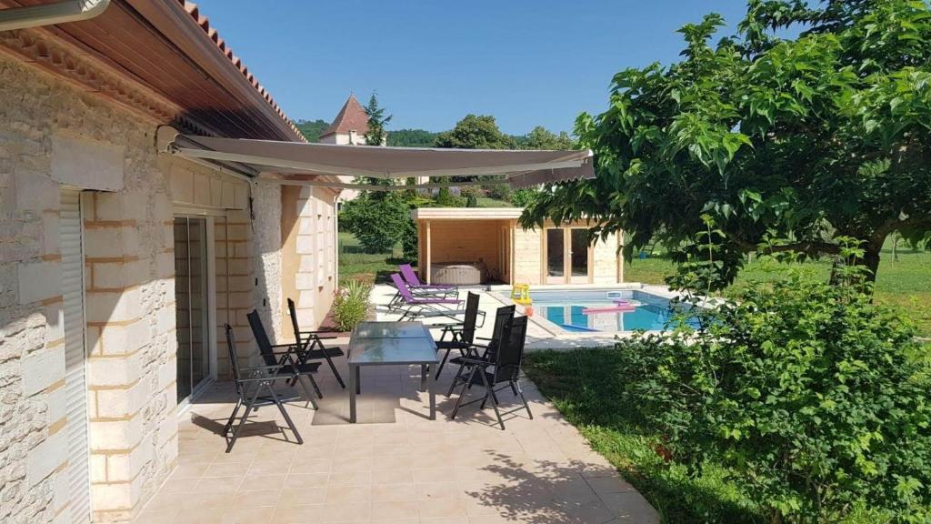 une terrasse avec des chaises et une table avec un parasol dans l'établissement Villa spacieuse 4 chambres Gîte les manoques, à Prayssac