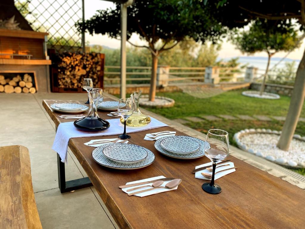 a wooden table with plates and wine glasses on it at Oasis Villa - Maisonette A in Almirón