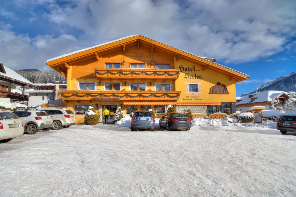 a large building with cars parked in front of it at Hotel Serles Superior in Dobbiaco