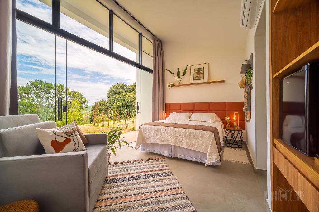 a bedroom with a bed and a large window at Pousada Boutique Mirante dos Adelphos in Socorro