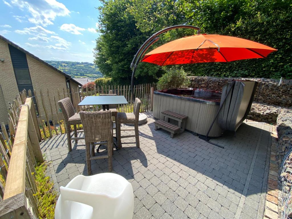 patio con mesa, sombrilla y bañera de hidromasaje en Livremont7 en Malmedy