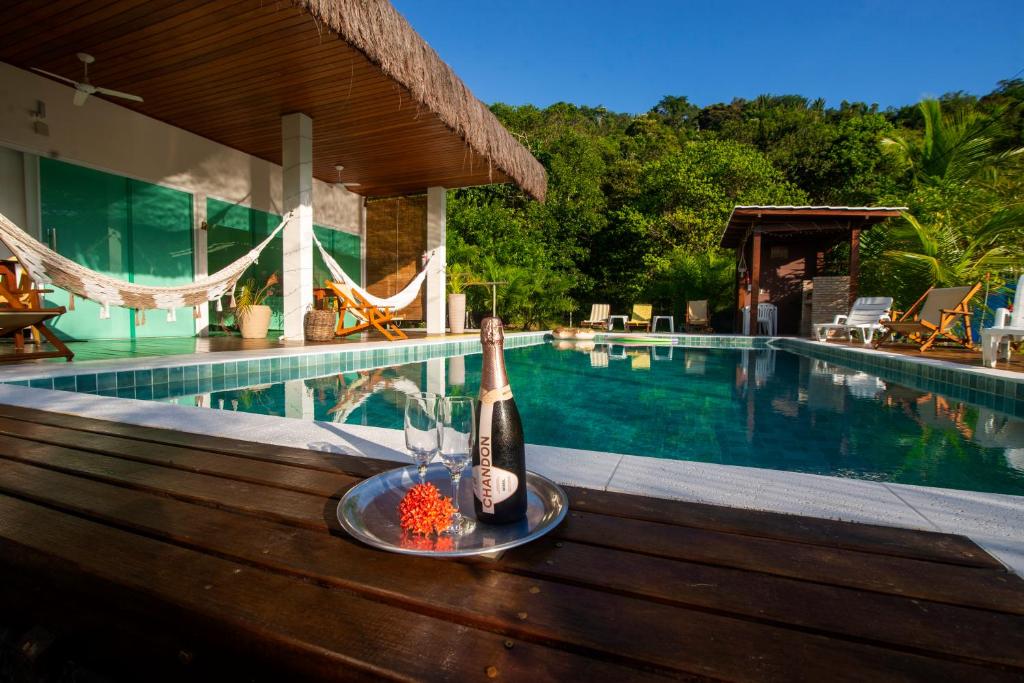 una botella de vino en una mesa junto a la piscina en Bella Gamboa casa de praia !Gamboa en Gamboa