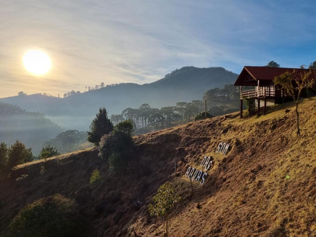 una casa en una colina con el sol en el cielo en Pousada Som das Aguas, en Gonçalves