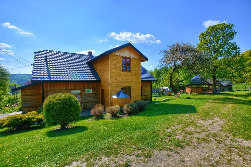 ein Holzhaus auf einem grünen Rasen in der Unterkunft Agroturystyka Chata za wsią in Uście Gorlickie
