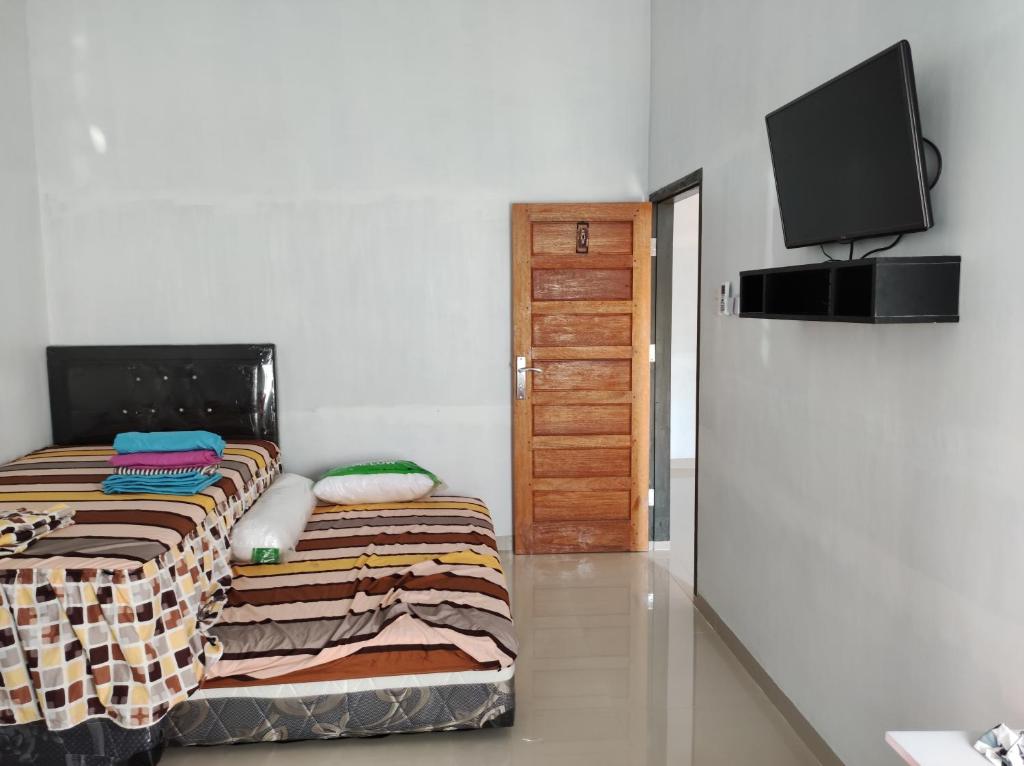 1 dormitorio con 2 camas y TV de pantalla plana en Cahaya kos putri, en Banda Aceh