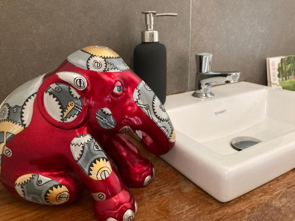 a red stuffed elephant sitting next to a sink at B&B De Grote Plaats in Hoogstraten