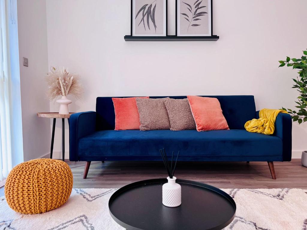 NEW Cosy 3BR Apartment With Private Garden In Olympic Park في لندن: أريكة زرقاء في غرفة المعيشة مع طاولة