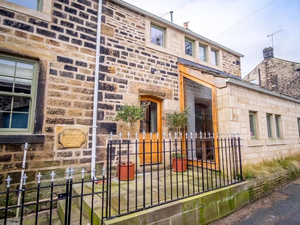 un antiguo edificio de ladrillo con una puerta amarilla en School Cottage, en Holmfirth