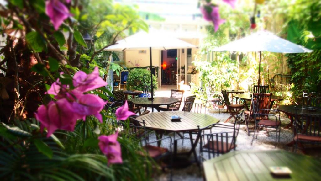 een patio met tafels en stoelen en paarse bloemen bij Privat Hotel Liberty Sitges in Sitges