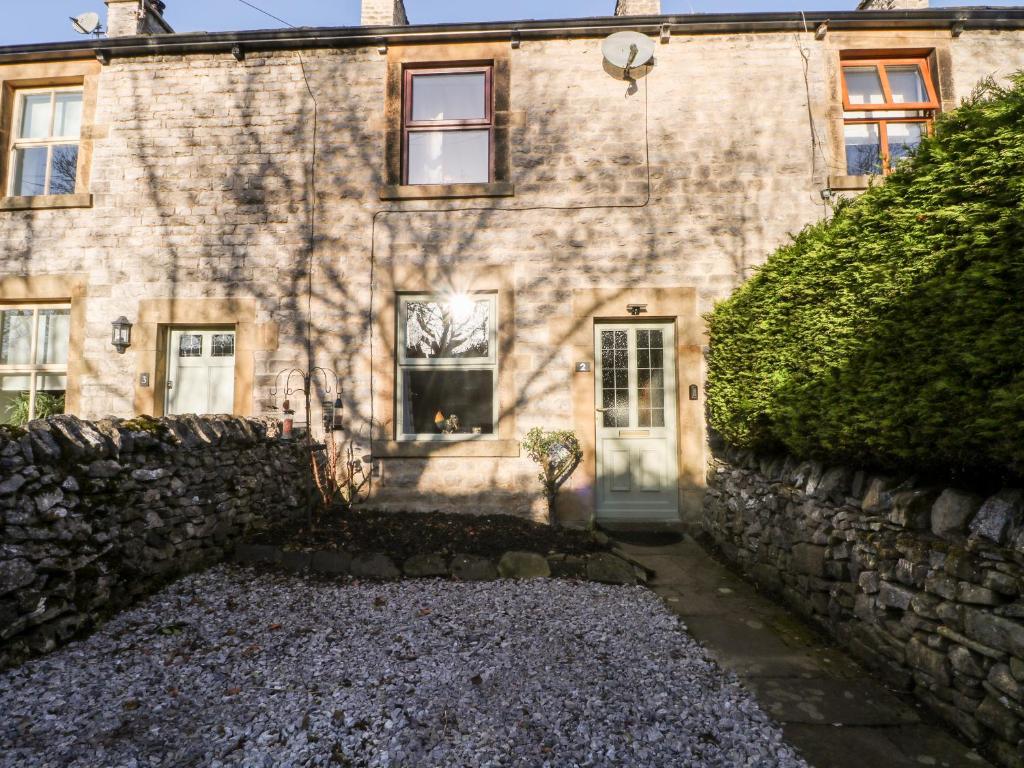 a stone house with a gravel driveway in front of it at 2 Oddfellows Cottages in Hope