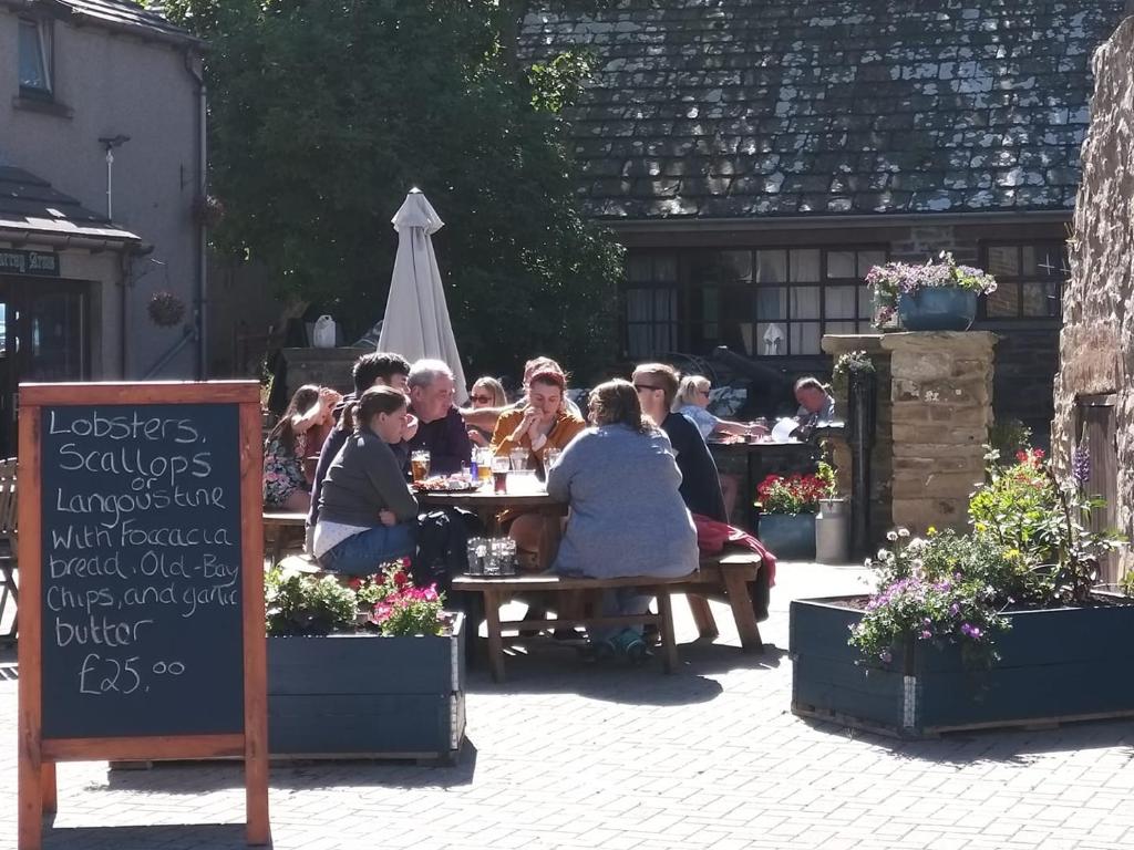 a group of people sitting at a table in a garden at Murray Arms Hotel and Seafood Restaurant, Orkney in Saint Margarets Hope