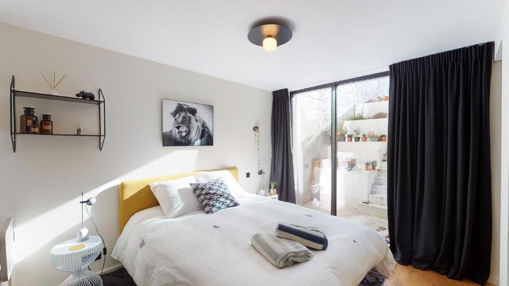 a bedroom with a bed and a large window at Suite lumineuse à Saint-Gilles in Brussels