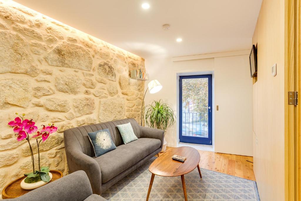 a living room with a couch and a stone wall at Riverside 2 Bedroom Apartment by DA'HOME in Porto
