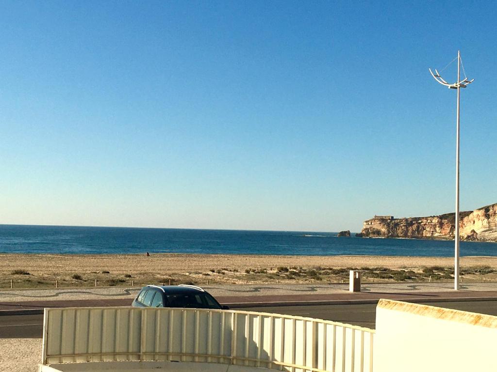 ナザレにあるCasa do Mar -Sea houseの風車付きのビーチの隣の駐車場