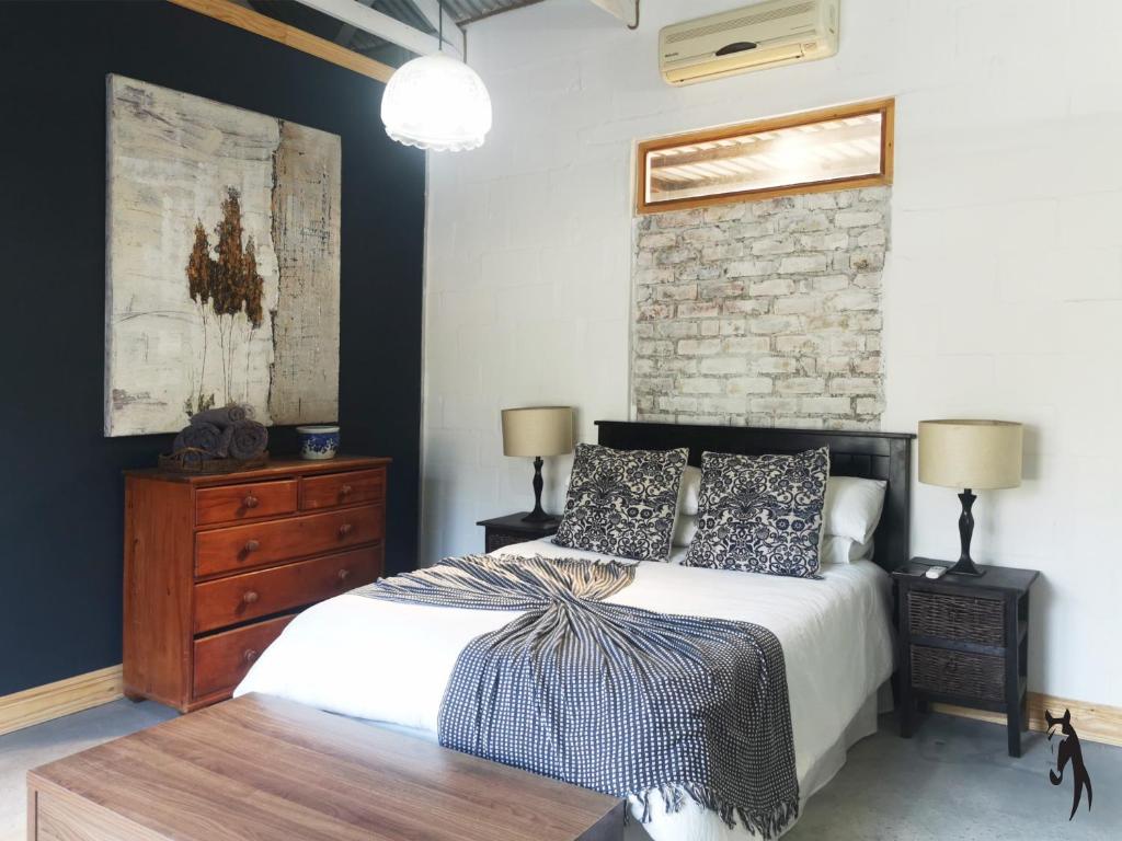 a bedroom with a bed and a brick wall at Ross Farms Guest Cottages in Wellington