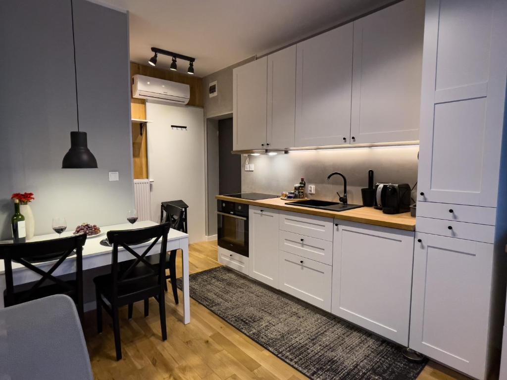 a kitchen with white cabinets and a table with chairs at URABN APARTMENTS Studio with garden No 2A Chorzów Katowice FREE PRIVATE PARKING in Chorzów