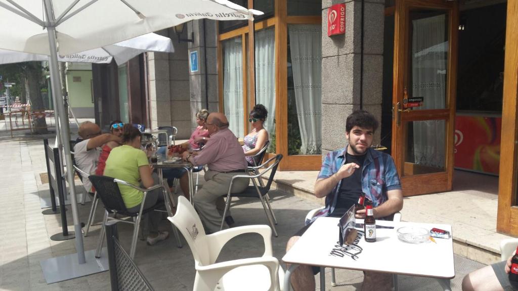 um homem sentado à mesa em frente a um guarda-chuva em Hostal Galicia em Figueres